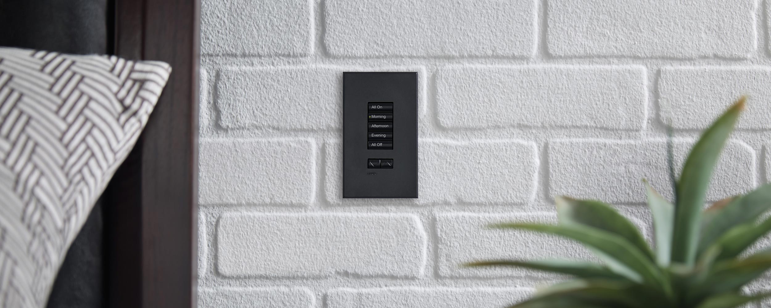 A simple red vase with white roses on a rustic wooden table, next to a minimal light switch on a white wall.